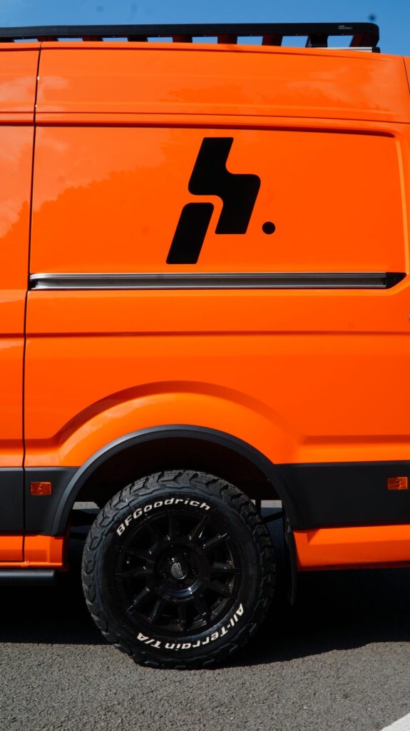 Orange van with black alloy wheels and all-terrain tyres fitted by Steadplan